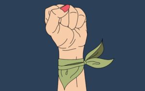 Mano con el puño en alto y con un pañuelo verde atado a la muñeca, símbolo de apoyo a al aborto libre y seguro